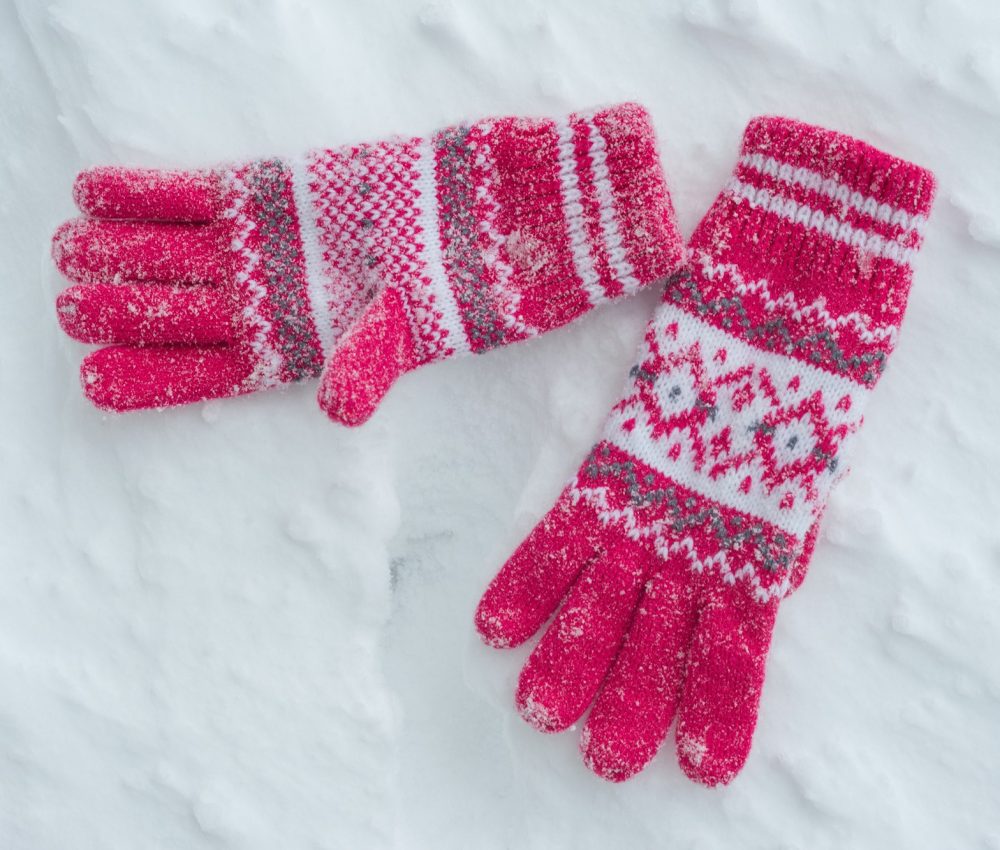 Snow covered gloves on snow. A Winter background